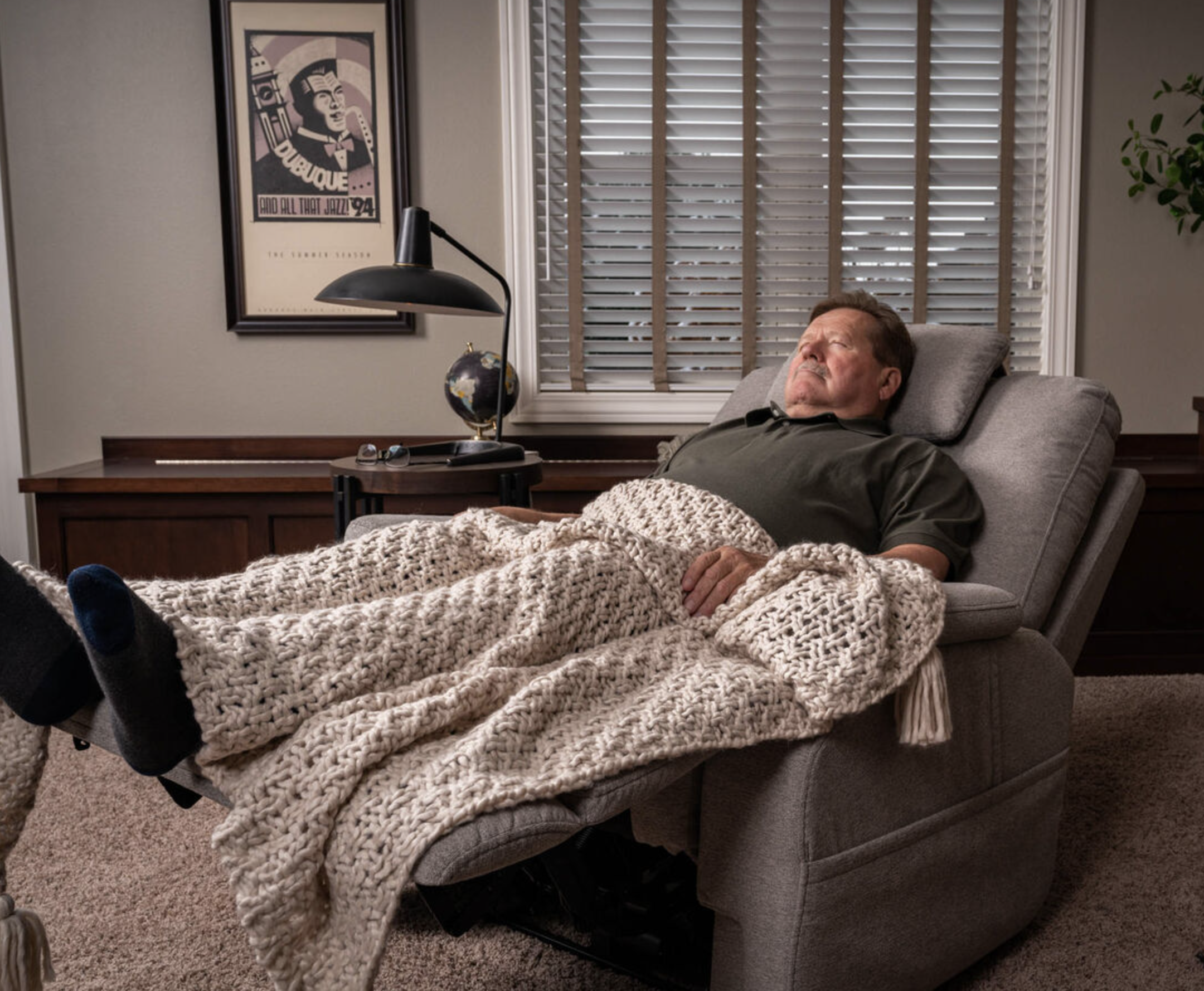 man with a blanket sleeping on a recliner 